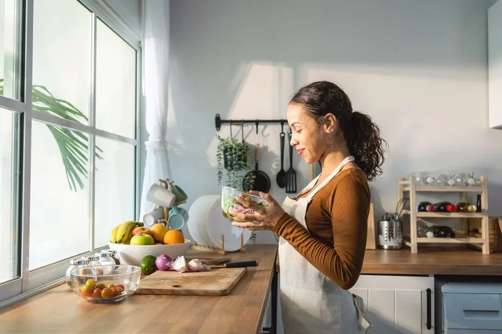 Woman reading at a kitchen bench in soft afternoon light